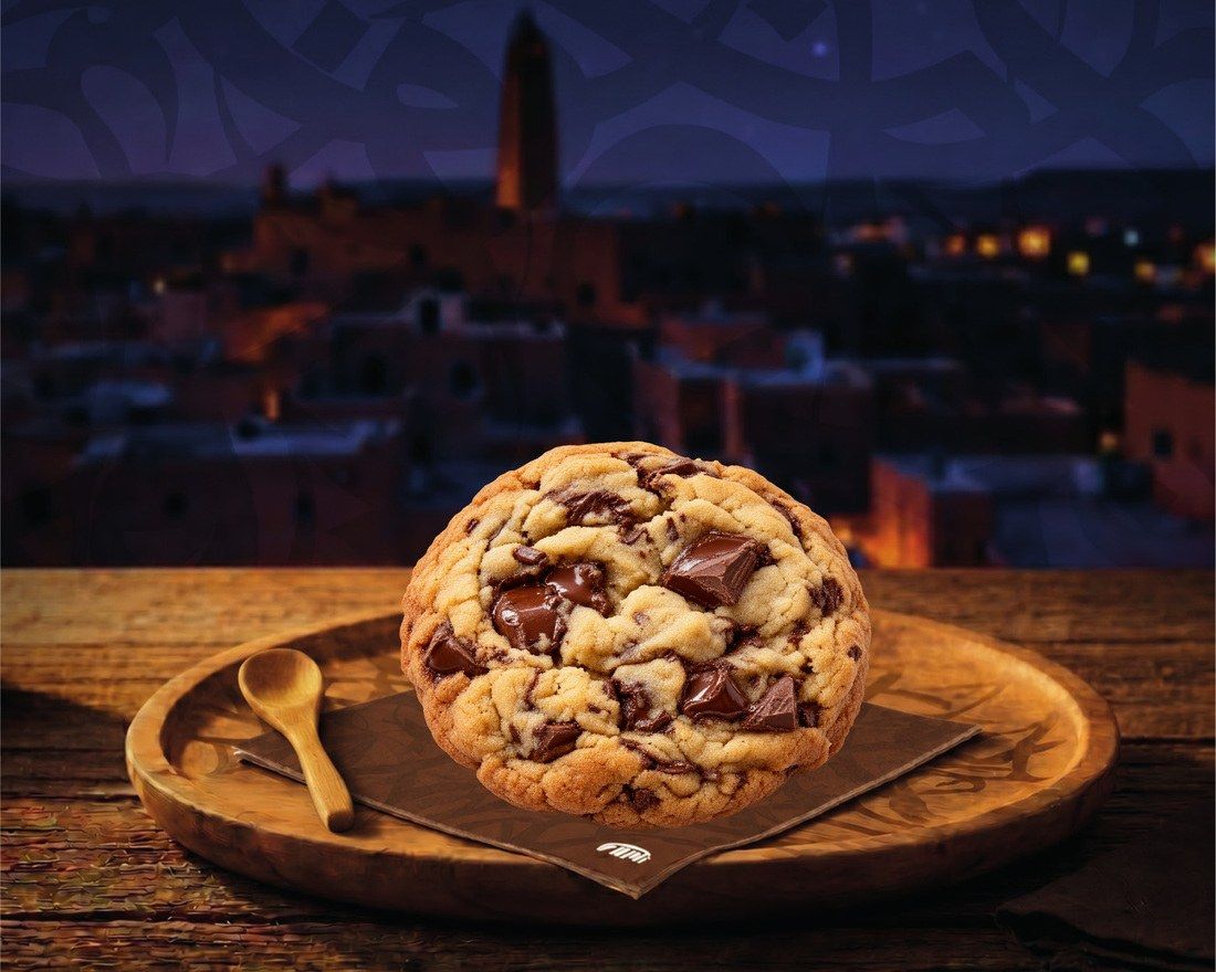 Un cookie aux gros éclats de chocolat, sur une serviette FAMI et un plateau en bois
