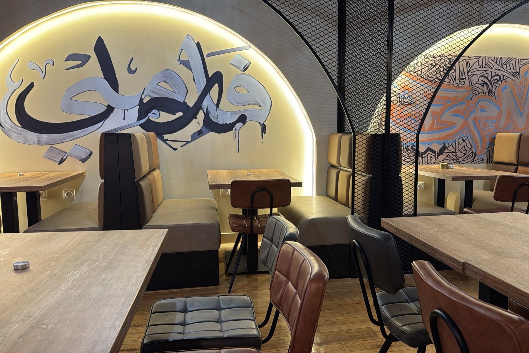Des banquettes sous deux arches éclairées, ornées de grandes calligraphies peintes